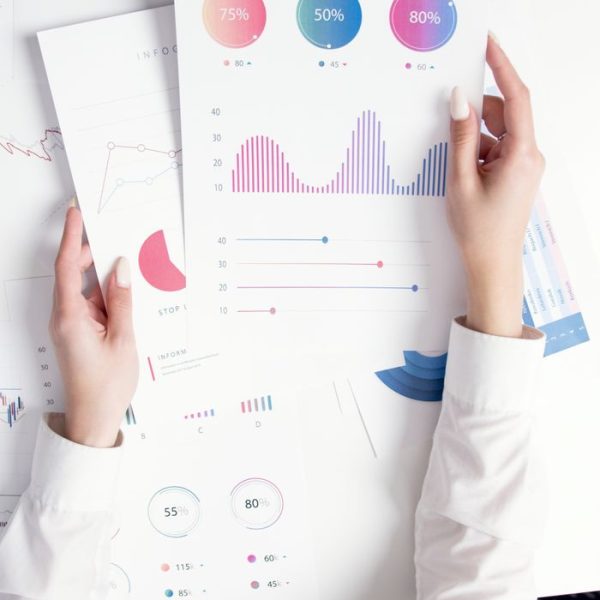 Close-up of hands analyzing colorful business data reports in an office setting.